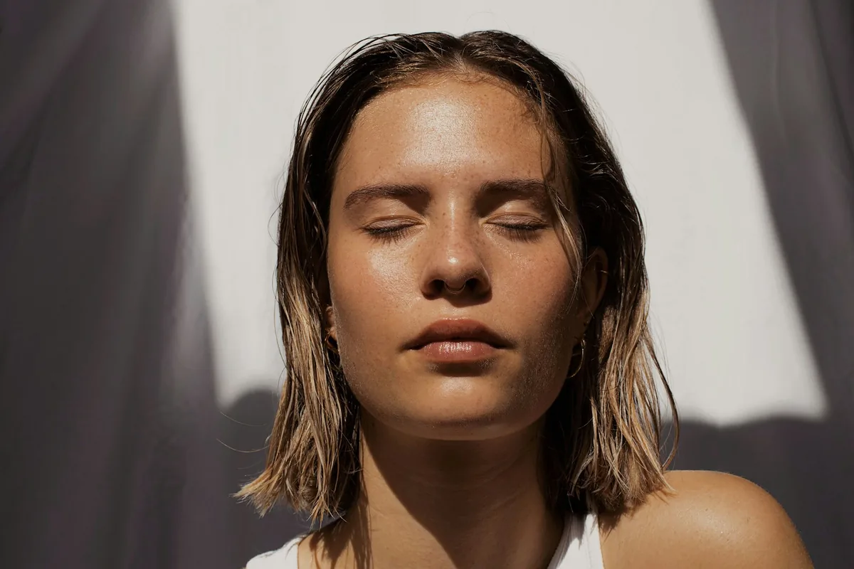 Vrouw met de ogen dicht in warm zonlicht